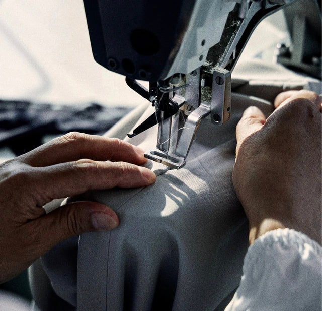Close-up of hands operating a sewing machine with a blurred background