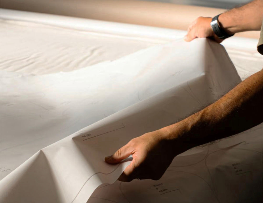 Person holding a large piece of white fabric with patterns on it.